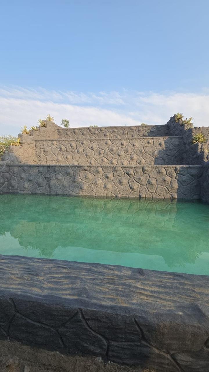 Stone-finish swimming pool with stepped rock terraces